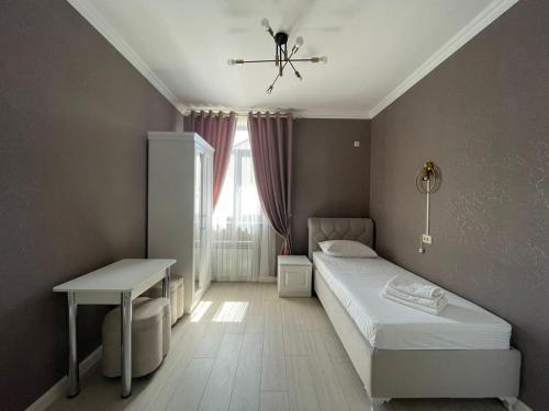 een slaapkamer met een bed, een tafel en een raam bij Keruen Deluxe in Taraz