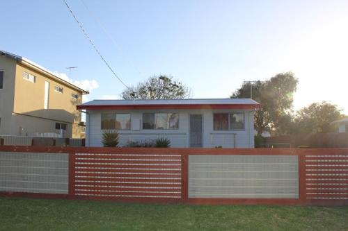a house with a red fence in front of it at Vista Bloom Hideaway in Cape Woolamai