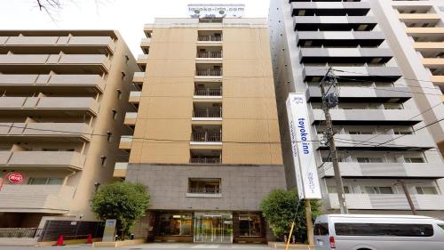a large apartment building with a van parked in front of it at Toyoko Inn Tokyo Ikebukuro Kita-guchi No.1 in Tokyo