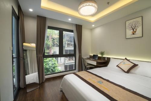 a bedroom with a bed and a desk and windows at Bao Hung Hotel & Apartment - Tran Quoc Vuong in Hanoi