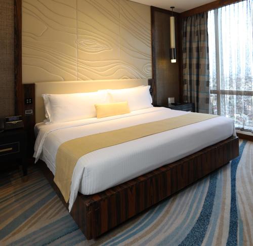 a large bed in a hotel room with a large window at Winford Resort and Casino Manila in Manila