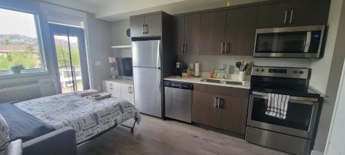 a kitchen with stainless steel appliances and a bed at Cozy Studio Suite, 15min walk to downtown in Kelowna