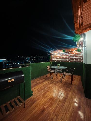 a room with a table and chairs on a balcony at night at Departamento con vista panoramica in Cusco