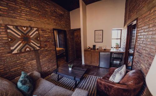 a living room with leather furniture and a brick wall at Casa Marron Valle de Guadalupe in Valle de Guadalupe