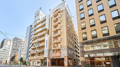 a building on a city street with tall buildings at Toyoko Inn Shin-Osaka Chuo-guchi Shinkan in Osaka
