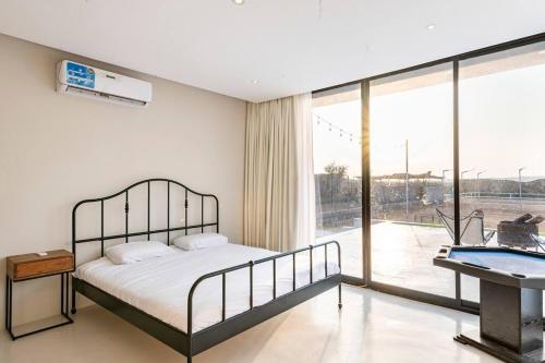 a bedroom with a bed and a large window at Desert farm gateway W/ pool & horse in Hunaywah