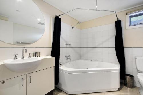 a white bathroom with a sink and a tub at White Crystal 206 in Mount Hotham