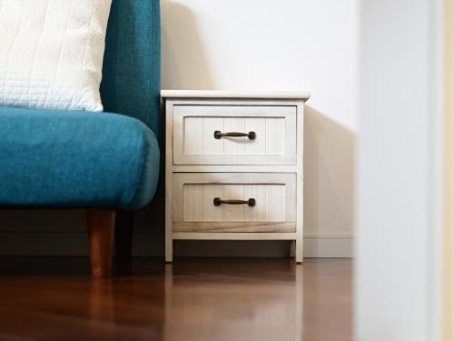 a bedside table with a blue chair next to it at Ocean Villa Tin Gala in Onna