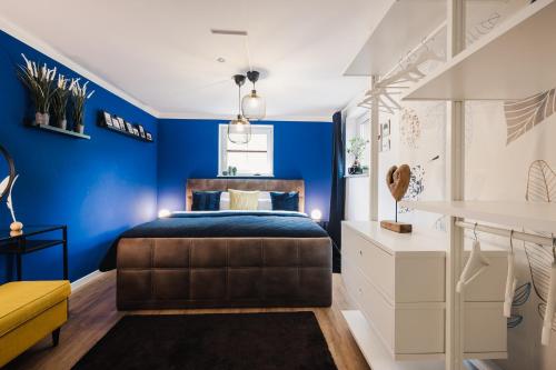 a bedroom with blue walls and a bed and a yellow chair at Ferienwohnung "UtTied" - komfortabel und modern! in Klausdorf Mecklenburg Vorpommern