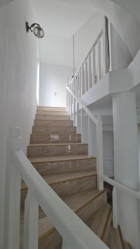 eine weiße Treppe mit Holzböden und weißen Geländern in der Unterkunft Casa Anne in Băile Herculane