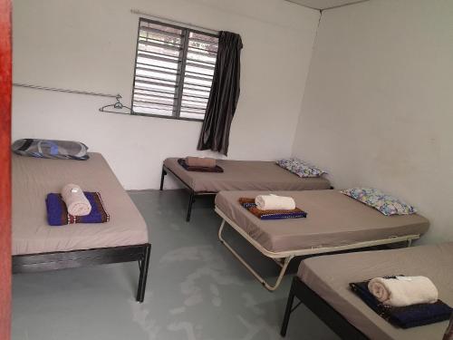 3 camas en una habitación con ventana en Tony’s Guesthouse at Teluk Bahang en Batu Ferringhi