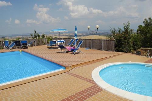 a swimming pool with chairs and a table and umbrella at Apartment Il Casino numero 5 in Laiatico