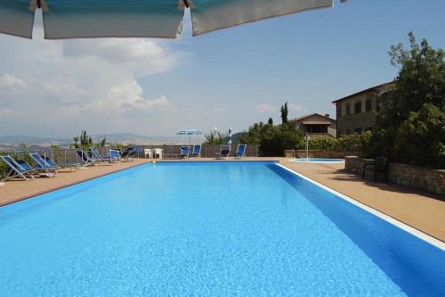 a large blue swimming pool with chairs and a building at Apartment Il Casino numero 5 in Laiatico