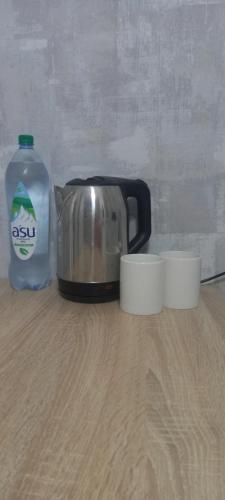 a tea kettle and a bottle of water on a table at Циолковского с кодовым замком in Uralsk