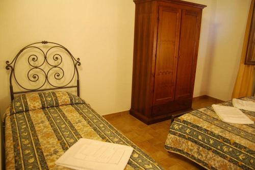 a bedroom with two beds and a wooden cabinet at Apartment Il Casino numero 5 in Laiatico