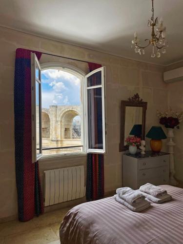 um quarto com uma cama e uma grande janela em Appartement aux Arènes em Arles