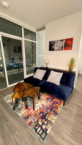 Brand New Starling Luxury Condo with Mountain Views في برنابي: غرفة معيشة مع أريكة زرقاء وطاولة