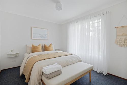 een witte slaapkamer met een bed en een raam bij 165 Back Beach Road Smiths Beach in Smiths Beach