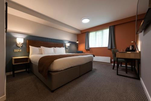 une chambre d'hôtel avec un lit et un bureau dans l'établissement Wilmslow Lodge, à Wilmslow