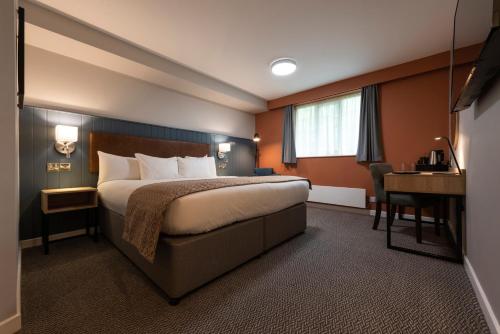 ウィルムズローにあるWilmslow Lodgeのベッドとデスクが備わるホテルルームです。