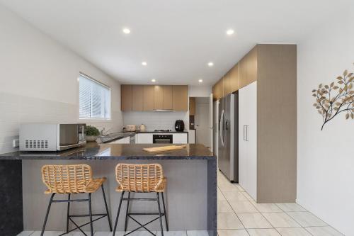 a kitchen with two bar stools at a counter at Retreat on Gairloch I Geelong River Hideaway in Geelong