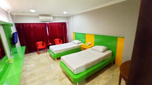 a bedroom with two beds and a table and chairs at Kita Hotel in Tanjung Pinang 