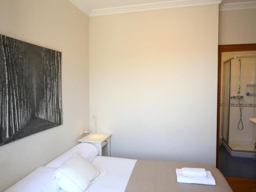 1 dormitorio con 1 cama blanca y una pintura en la pared en Centenario, en San Sebastián