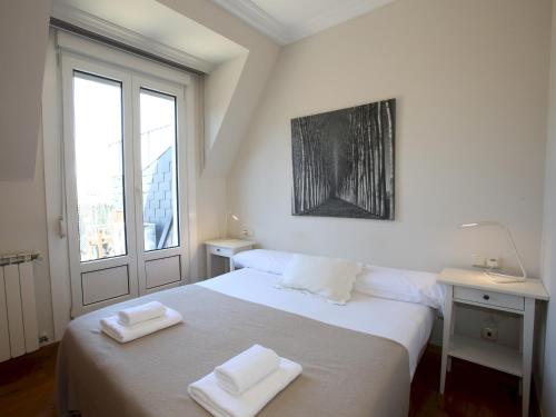 1 dormitorio blanco con 1 cama con 2 toallas en Centenario, en San Sebastián