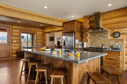 a kitchen with wooden walls and a counter with stools at Stone Skipper Lodge by KABINO Waterfront Hot Tub Private Bath In Every Bedroom FirePit Mtn Views WiFi Grill in Island Park