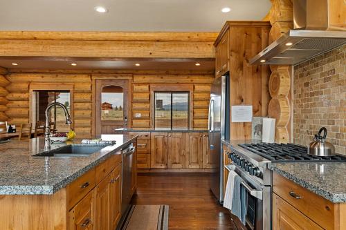 a kitchen with wooden cabinets and a stove top oven at Stone Skipper Lodge by KABINO Waterfront Hot Tub Private Bath In Every Bedroom FirePit Mtn Views WiFi Grill in Island Park