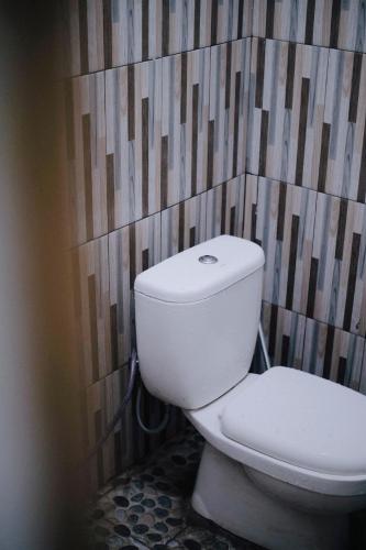 a white toilet in a bathroom with a wall at D Black Houze Banyuwangi in Banyuwangi