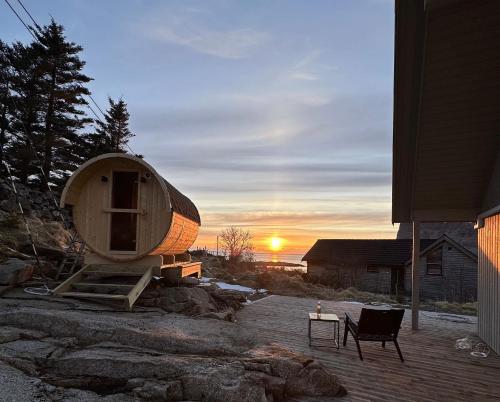 a round house sitting on a deck with the sunset in the background at Haukland beach panorama in Offersøya