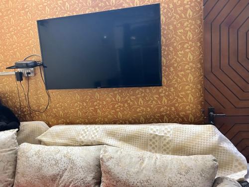 una TV a schermo piatto appesa a un muro di Arora’s Mansion a Ghaziabad