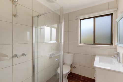 a bathroom with a toilet and a glass shower at Seven on Ophir in Ventnor