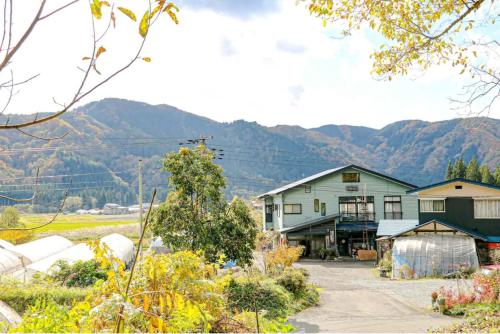 a house with mountains in the background at Farm Inn Seisetsukan in Senboku