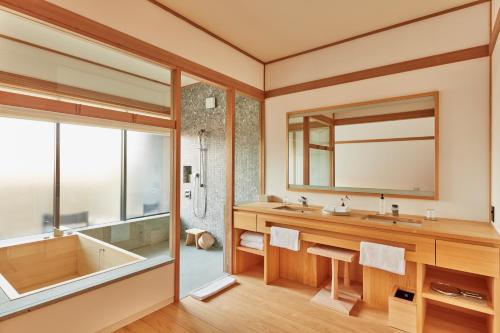 a bathroom with a tub and a sink and a mirror at Azumi Setoda in Onomichi
