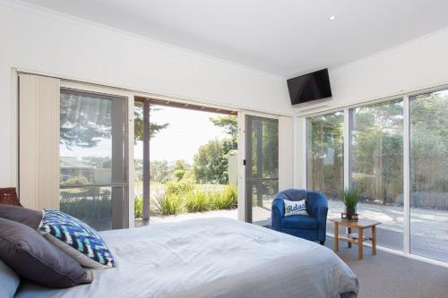 Schlafzimmer mit einem Bett und einem großen Glasfenster in der Unterkunft Red Rocks Beach Retreat Free Wifi and Foxtel in Cowes