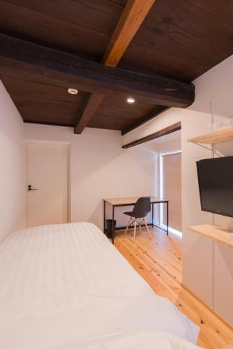 a bedroom with a white bed and a desk at FARMSTAY miyuki-street "Goen" in Ukiha