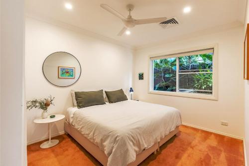 a white bedroom with a bed and a window at Celeste 26 Bonito Street light filled pet friendly house in Corlette