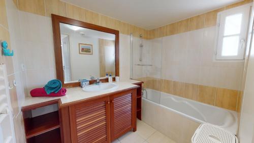een badkamer met een wastafel, een bad en een spiegel bij Le Cottage des Fontenelles in Coëx