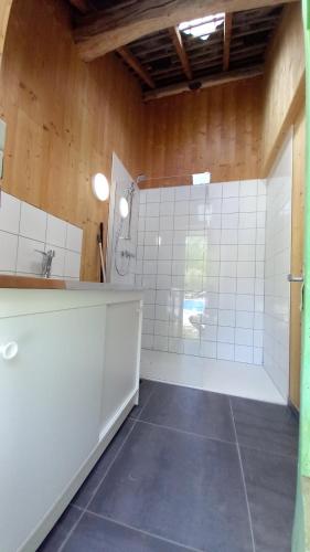 uma casa de banho com um chuveiro e uma parede de azulejos brancos. em Cabane du Druide Domaine de Fangorn em Glux