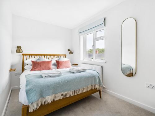 Schlafzimmer mit einem Bett mit rosa Kissen und einem Spiegel in der Unterkunft Fairwinds in Portreath