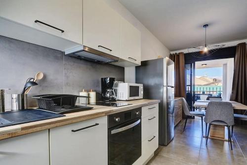 una cucina con elettrodomestici bianchi e una sala da pranzo di Leu Burgot 1, Appartement 13 a Saint-Leu