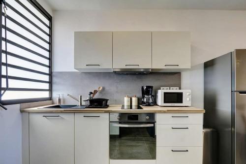 una cucina con armadietti bianchi e forno a microonde di Leu Burgot 1, Appartement 13 a Saint-Leu