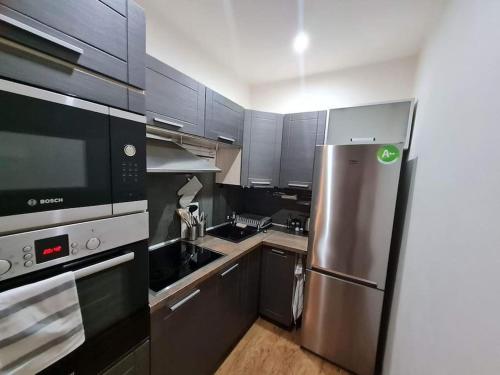 La cuisine est équipée d'un réfrigérateur en acier inoxydable et de placards gris. dans l'établissement apartman MI, à Michalovce
