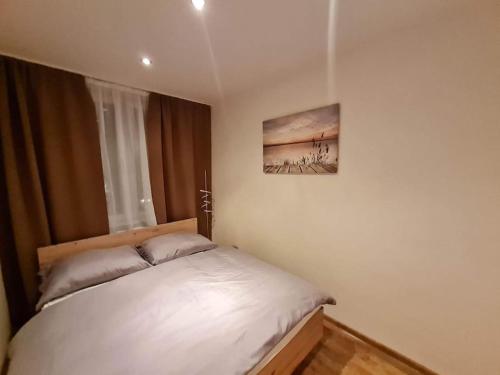Un dormitorio con una cama blanca con una foto en la pared en apartman MI, en Michalovce