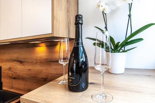 a bottle of wine and two wine glasses on a table at Apartments Ursus in Bled