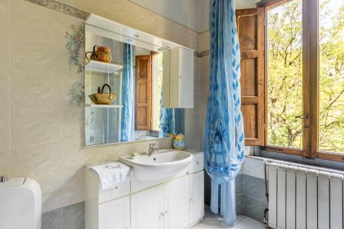 een badkamer met een wastafel, een spiegel en een raam bij Casale Poli in Borgo a Mozzano