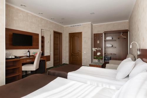a hotel room with two beds and a desk at Optima Collection Gallery Poltava in Poltava
