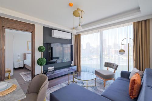 un soggiorno con divano blu e una grande finestra di Air Başakşehir Residence by NewInn a Basaksehir